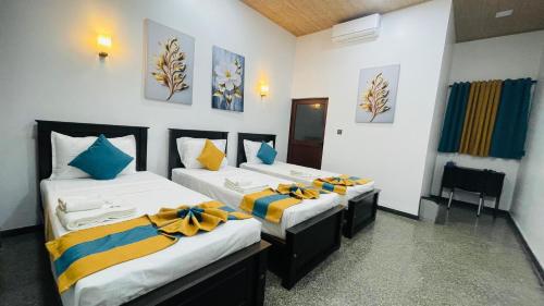 a room with three beds with yellow and blue pillows at The Sanctum in Talaimannar