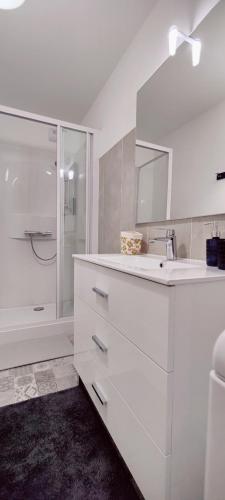 une salle de bain blanche avec un lavabo et une douche dans l'établissement Le Corsaire, à Granville