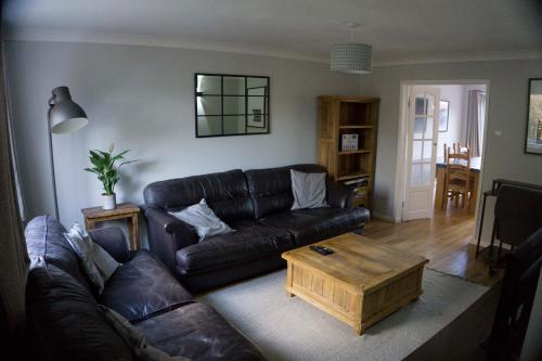 a living room with a leather couch and a coffee table at Entire 3-bed house near Cheltenham racecourse and town in Gloucestershire