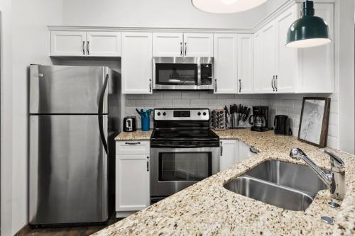 a kitchen with white cabinets and a stainless steel refrigerator at Luxury 3B Mountain Views- Pool & Hot Tub -Sleeps 10 in Canmore