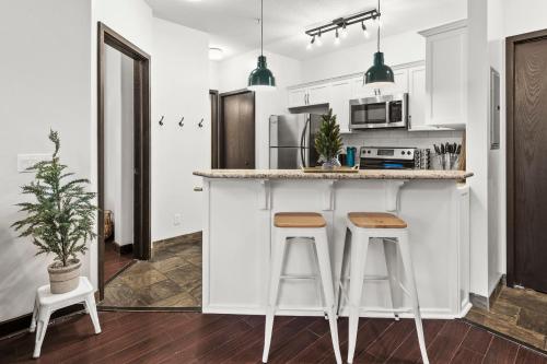 a kitchen with white cabinets and bar stools at Luxury 3B Mountain Views- Pool & Hot Tub -Sleeps 10 in Canmore