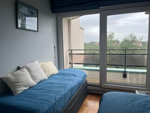 - un canapé bleu dans une chambre avec une grande fenêtre dans l'établissement Le Touquet magnifique appartement 3 chambres vue sur mer, à Le Touquet-Paris-Plage