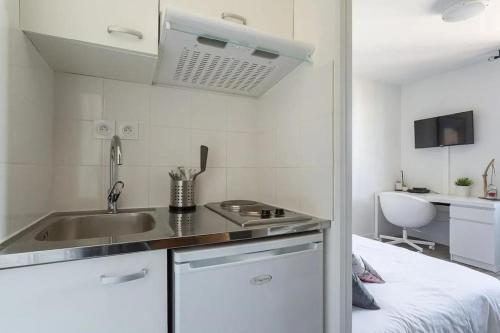 - une petite cuisine blanche avec un évier et un lit dans l'établissement ONE NIGHT in LYON - UNE NUIT à LYON, à Lyon