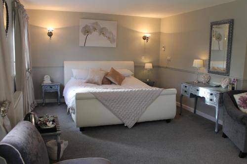 a bedroom with a bed and a table and a mirror at The Swan Motel, Gillingham in Beccles