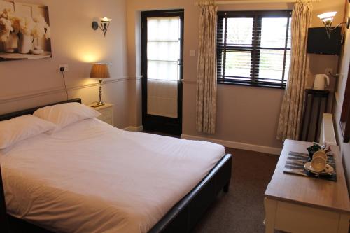a bedroom with a bed and a desk and a window at The Swan Motel, Gillingham in Beccles