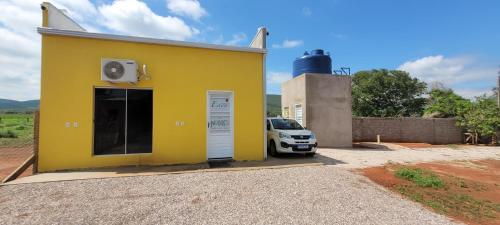a yellow building with a car parked next to it at Jardim do Éden Hostel e Camping in Estivado