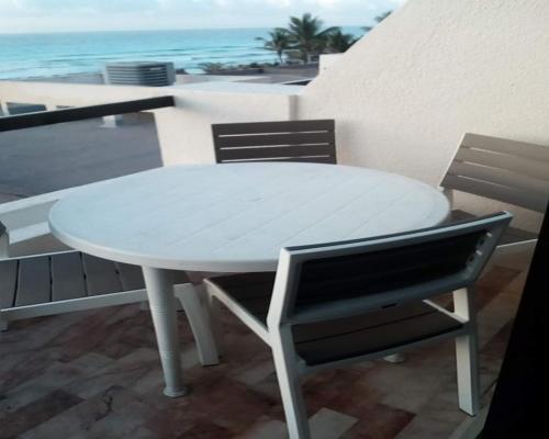 a white table and chairs on a balcony with the ocean at Condominio Privado Villas Marlin Zona Hotelera Cancun in Cancún