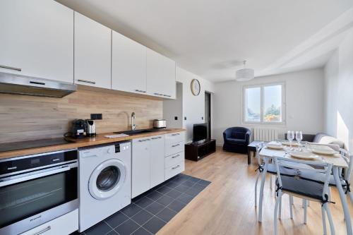 - une cuisine avec des placards blancs et une table avec un lave-linge dans l'établissement Appartement Lumière Normande - Welkeys, à Cabourg