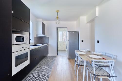 une cuisine avec une table avec des chaises et un micro-ondes dans l'établissement Appartement Sérénité Normande - Welkeys, à Cabourg