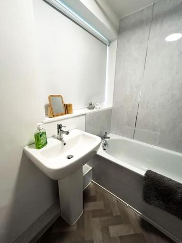 a white bathroom with a sink and a bath tub at 3 Double Bedrooms, Lancashire Townhouse, Free Parking in Upholland