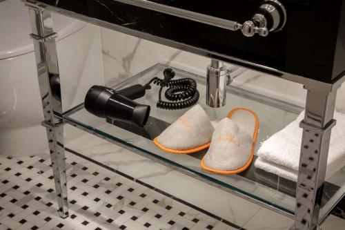 a glass shelf with two pairs of shoes and a phone at Hotel Canada, BW Premier Collection in Rome