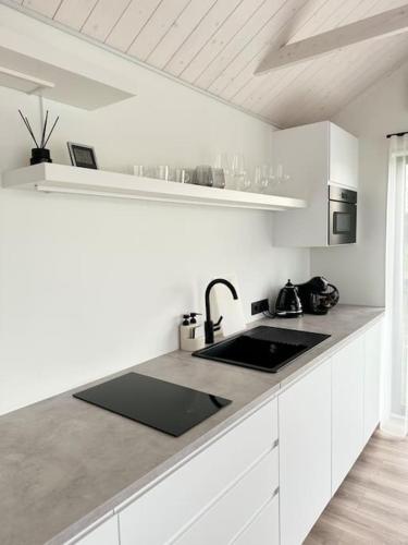 a white kitchen with a sink and a counter top at Gabiežezers Holiday House, 30km from Riga in Cena