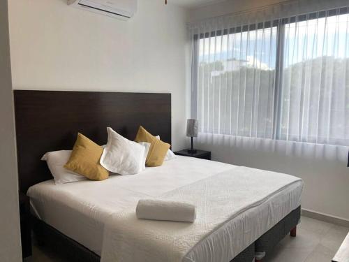 ein Schlafzimmer mit einem großen Bett mit gelben und weißen Kissen in der Unterkunft Acogedor Fast WIFI 5ta Avenida in Playa del Carmen