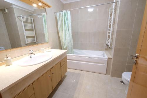 ein Badezimmer mit Waschbecken, Badewanne und Toilette in der Unterkunft high standard rental in a quality residence with pool, tennis and view of the ocean in antas esposende 12 people in Estrada