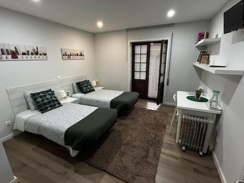 a bedroom with two beds and a table and a desk at Casa Pirosa2 in Aveiro