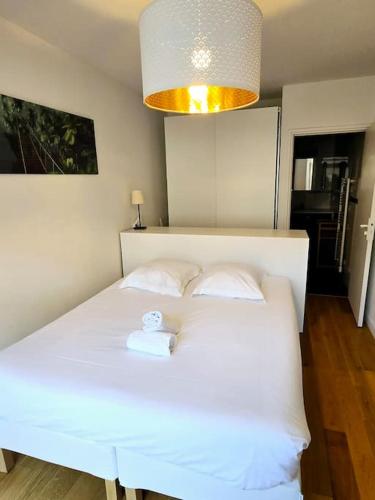 - une chambre avec un lit blanc et une lumière au-dessus dans l'établissement Appartement Grand T2 Hypercentre, à Bordeaux