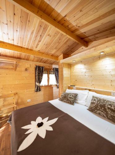 a bed in a log cabin with a flower on it at Stura River Village RAFTING in Gaiola