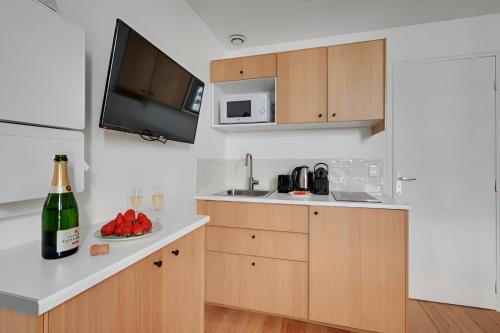- une cuisine avec une bouteille de vin et une assiette de fruits dans l'établissement 137-Suite Ella Great 1 BDR APT centre de Paris, à Paris