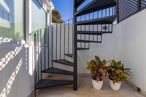 a black spiral staircase with two potted plants at CAMINITO REY & BANDERAS SPA Relax in Carratraca