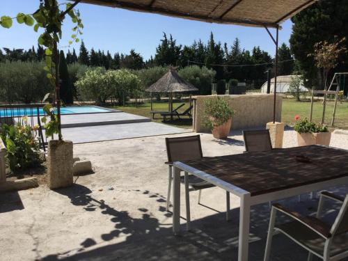 a patio with a table and chairs and a pool at beautiful provencal mas with pool in barbentane, close to avignon, sleeps 8. in Barbentane