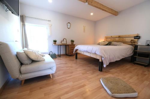 a bedroom with a bed and a couch and a chair at beautiful provencal mas with pool in barbentane, close to avignon, sleeps 8. in Barbentane