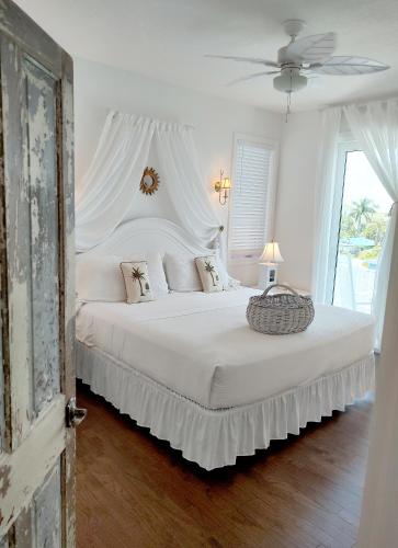 a bedroom with a large white bed with a fan at Bungalow Beach Resort in Bradenton Beach