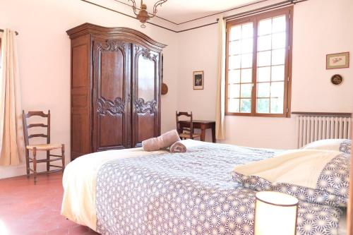 a bedroom with a bed and a wooden cabinet at typical mas provençal with swimming pool in a small hamlet near mouriès in the alpilles in provence- 8 persons in Mouriès