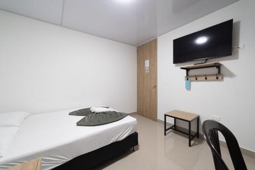 a bedroom with a bed and a tv on the wall at Hotel Doxa in Medellín