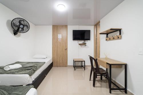 a hotel room with a bed and a desk and a tv at Hotel Doxa in Medellín