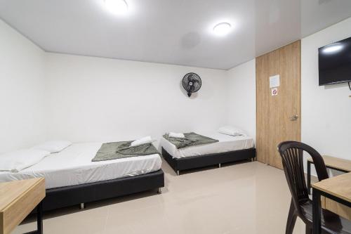 two beds in a room with a table and a desk at Hotel Doxa in Medellín
