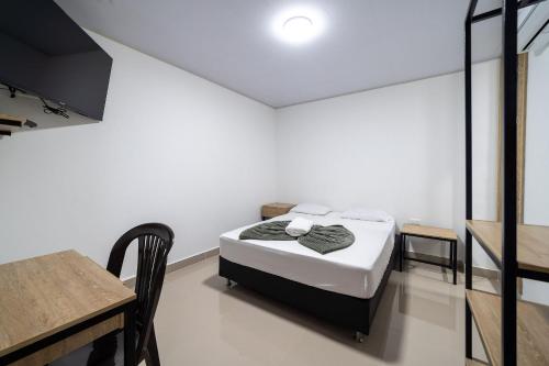 a small bedroom with a bed and a table at Hotel Doxa in Medellín