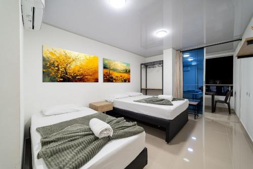 a bedroom with two beds and a dining room at Hotel Doxa in Medellín
