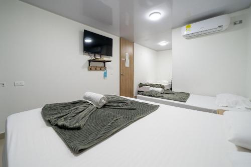 two beds in a room with a tv on the wall at Hotel Doxa in Medellín