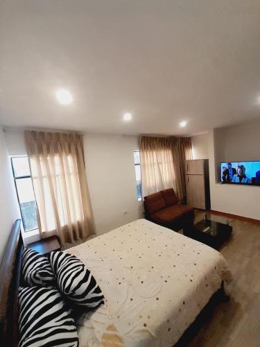 a bedroom with a bed and a couch and a television at DEPA CAMa QUEEN in Huancayo