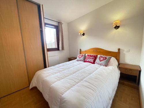 une chambre avec un grand lit blanc avec des oreillers rouges dans l'établissement Appartement cosy avec piscine, animaux admis et parking à Flumet - FR-1-505-206, à Flumet