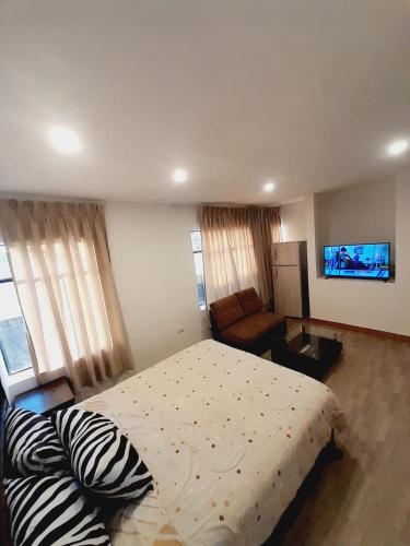 a bedroom with a bed and a couch and a television at DEPA CAMa QUEEN in Huancayo