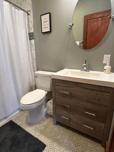 a bathroom with a toilet and a sink and a mirror at Get Kozy in Kenwood in Syracuse