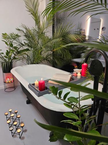 a bathroom with a bath tub with candles and plants at Black Walnut House with indoor outdoor fireplace in Izvoarele