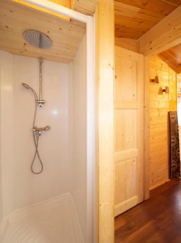 a shower in a wooden room with a door at Stura River Village RAFTING in Gaiola
