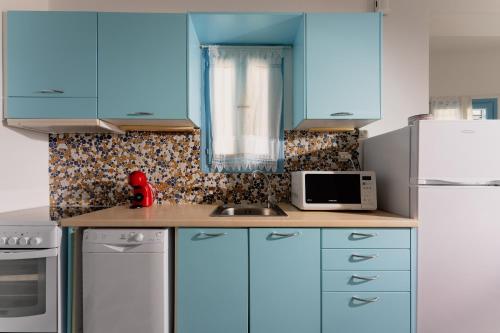 a kitchen with blue cabinets and a white refrigerator at Galazio studios in Angairiá