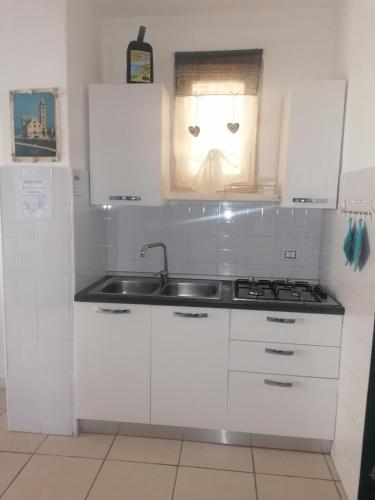 a kitchen with white cabinets and a sink and a window at Travel and Living in Trani