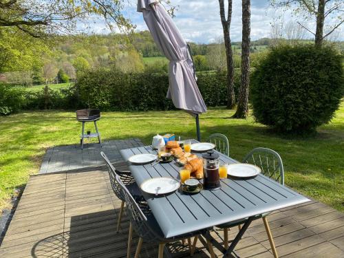 a picnic table with an umbrella on a deck at Le petit Fournil - Vue sur le bocage normand - 4p in Neuville-sur-Touques