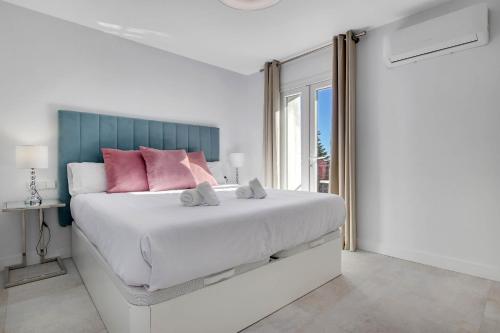 a white bedroom with a large bed with pink pillows at CAMINITO REY & BANDERAS SPA Relax in Carratraca