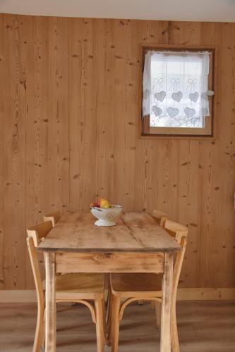 - une table en bois avec des chaises et une corbeille de fruits dans l'établissement Chez Colette - Appartement à la montagne, à Demi-Quartier