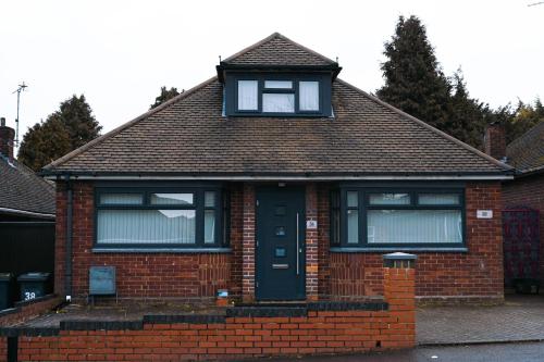 a red brick house with a black door and windows at Instant Home in Luton