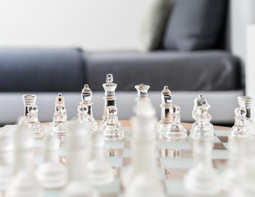 a chess set on a glass chess board on a table at Unique Penthouse with Gallery and Mountain View in Kandersteg
