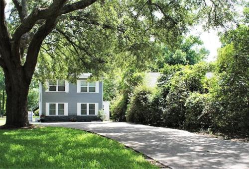 a house with a tree in front of a driveway at Golf Course-Front 2-Bedroom Apartment in Charleston
