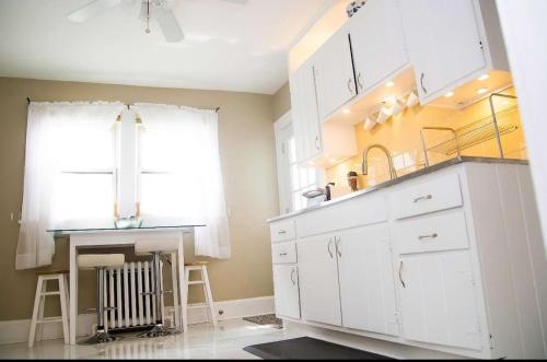 a kitchen with white cabinets and a sink and a window at Sunshine Room by harbor downtown beach I-95&Train in Stamford