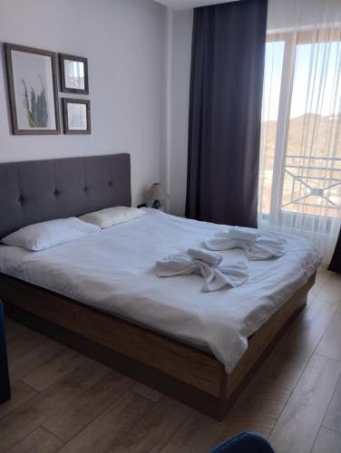 a bedroom with a bed with white sheets and a window at Milmari apartman SAN-28 in Kopaonik