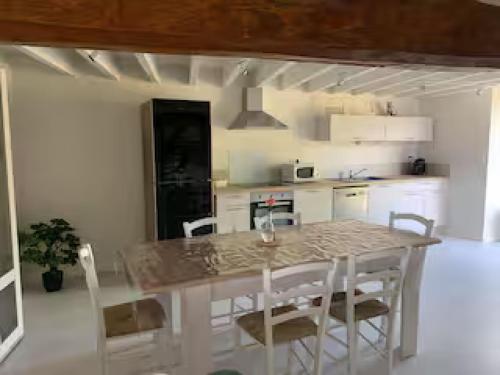 une cuisine blanche avec une table et des chaises dans l'établissement La Grande Hogue, à Dragey-Ronthon